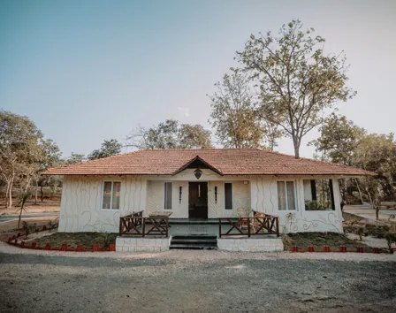 Woodland cottage with a tiled roof and wooden railing at Palash Jungle Resort