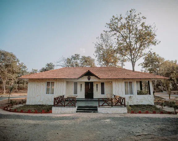 Woodland cottage with a tiled roof and wooden railing at Palash Jungle Resort
