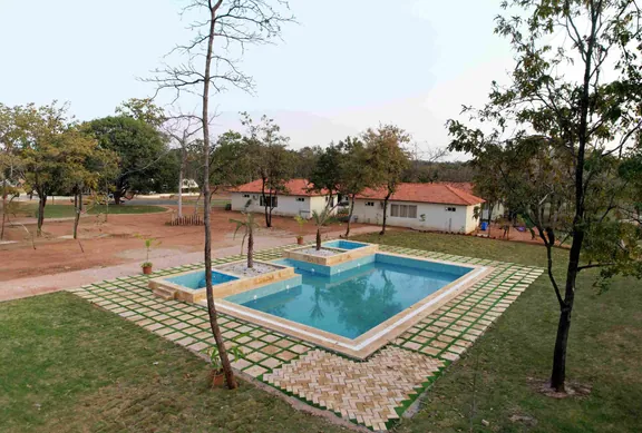 Swimming pool with lawns and cottages at Palash Jungle Resort