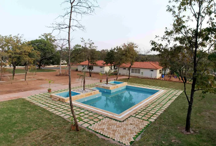 Swimming pool with lawns and cottages at Palash Jungle Resort