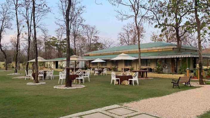 Lawn with dining tables and umbrellas in front of the banquet hall at Palash