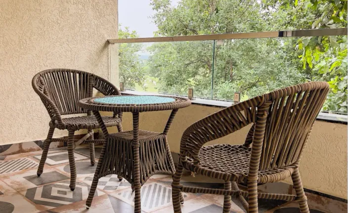 Cane chairs and a table on a patio at Palash Jungle Resort