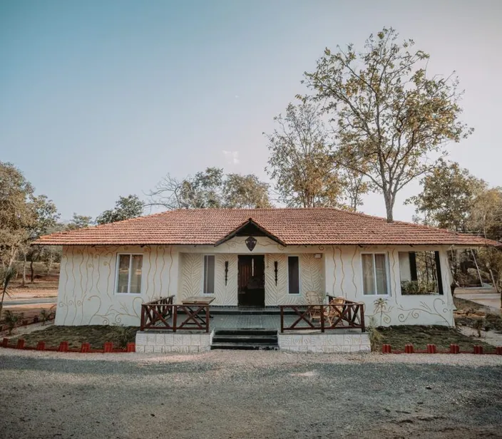 Woodland cottage with a tiled roof and wooden railing at Palash Jungle Resort