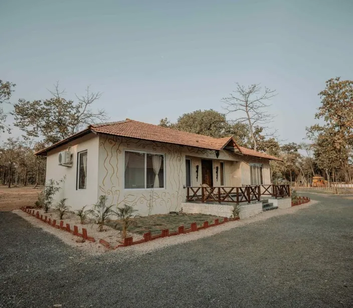 Woodland cottage exterior with a tiled roof at Palash Jungle Resort