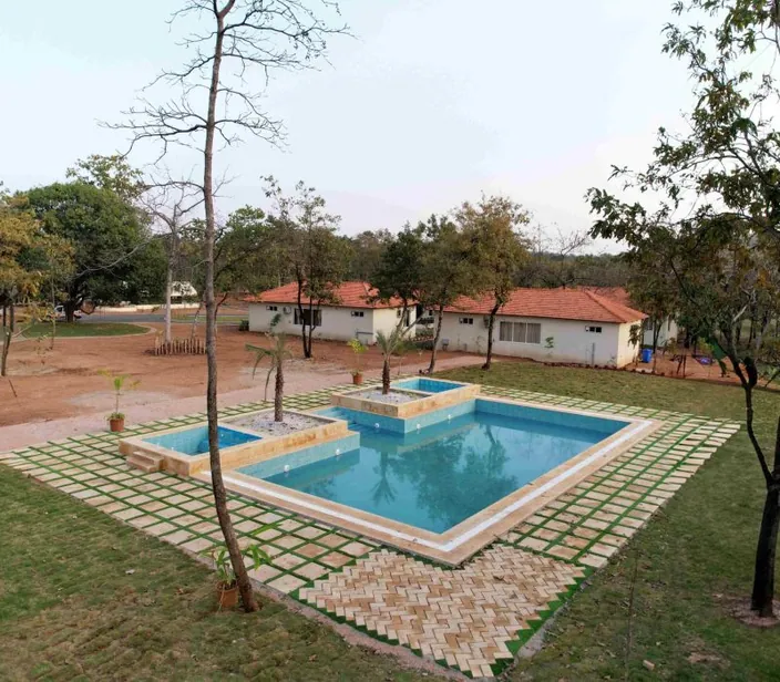 Swimming pool with lawns and cottages at Palash Jungle Resort
