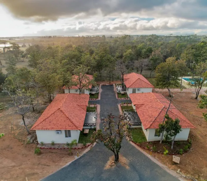 Aerial view of the cottages with hills in the distance at Palash Jungle Resort