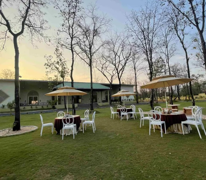 Lawn dining tables under umbrellas at dusk