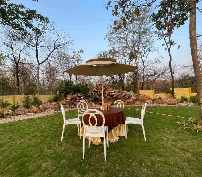 Dinner table with white chairs and an umbrella on the lawn